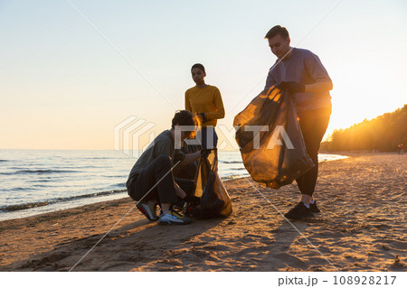 Earth day. Volunteers activists collects garbage cleaning of beach coastal zone. Woman and mans puts plastic trash in garbage bag on ocean shore. Environmental conservation coastal zone cleaning Earth day. Volunteers activists collects garbage cleaning of beach coastal zone. Woman and mans puts plastic trash in garbage bag on ocean shore. Environmental conservation coastal zone cleaning 108928217