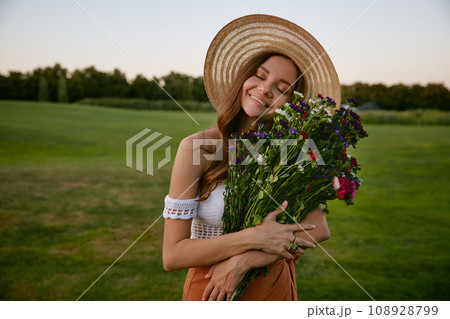 Beautiful hipster woman holding bunch of wildflower Beautiful hipster woman holding bunch of wildflower 108928799