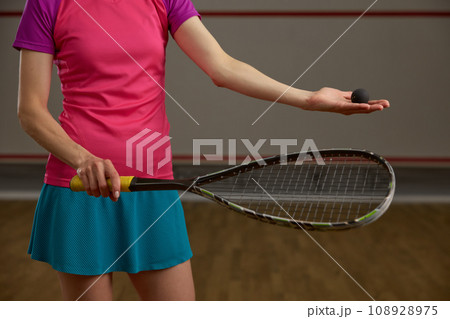 Closeup cropped view on female squash player holding racket and ball Closeup cropped view on female squash player holding racket and ball 108928975