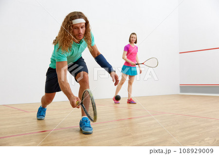 Young sportive couple practicing squash at sport club court Young sportive couple practicing squash at sport club court 108929009