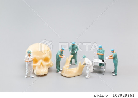 Miniature people Doctor with a giant human skull on a grey background 108929261