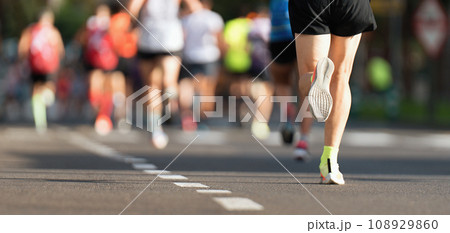 Marathon runners running on city road, large group of runners, close-up legs runners running sport marathon, male jogging race in asphalt road, athletics competition Marathon runners running on city road, large group of runners, close-up legs runners running sport marathon, male jogging race in asphalt road, athletics competition 108929860