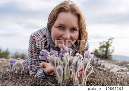 Dream grass woman spring flower. Woman lies on the ground and hugs flowers pasqueflower or Pulsatilla Grandis flowers 108931054