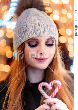 Christmas mood. Woman with long hair in sity decorated for Christmas. She is dressed in a black coat. 108931069