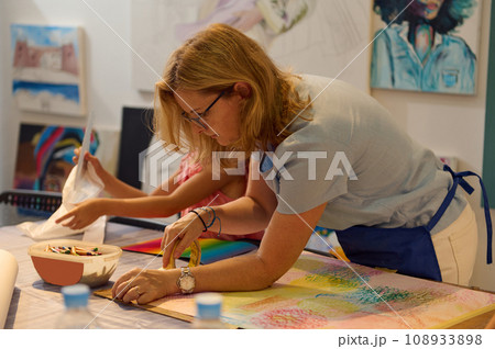Creative woman artist teacher during her work in art gallery or workshop. Female painter teaches art to a little student 108933898