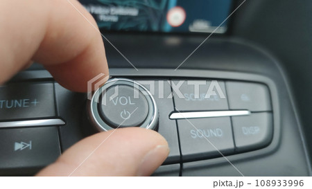 Macro close-up, turning down the volume of the car radio Macro close-up, turning down the volume of the car radio 108933996