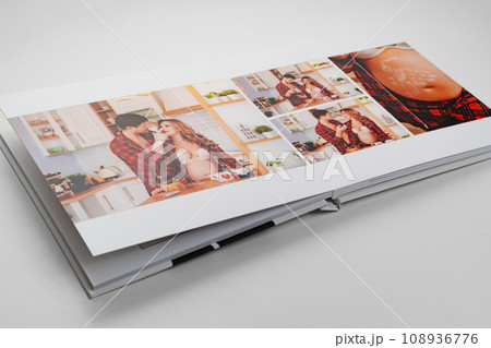 The pages of a photo book with color photos of a pregnant blonde and a man.  108936776