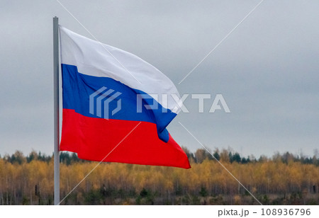 The white-blue-red flag of the Russian Federation is flying in the wind against a cloudy sky. The white-blue-red flag of the Russian Federation is flying in the wind against a cloudy sky. 108936796