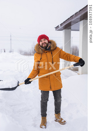 Man removing snow and ice from the sidewalk in front of house. Winter season 108937391
