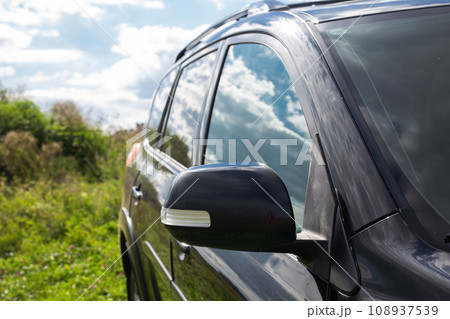Side rear view mirror on a modern black car outdoor. Close-up of automobile detail 108937539
