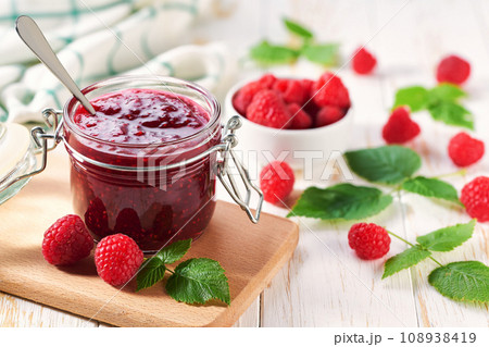 Homemade raspberry confiture in a jar on a white wooden table. Delicious homemade natural raspberry jam. 108938419