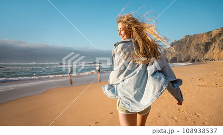 Woman running beach and smiling for camera Woman running beach and smiling for camera 108938537