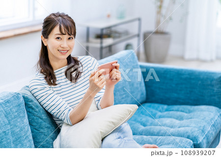 リビングでスマホを操作する女性。 リビングでスマホを操作する女性。 108939207
