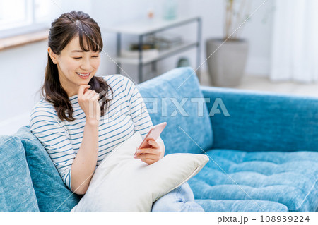 リビングでスマホを操作する女性。 リビングでスマホを操作する女性。 108939224