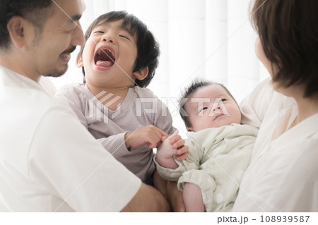 赤ちゃんを抱くパパとママ 仲良し4人家族みんなでいい笑顔 赤ちゃんを抱くパパとママ 仲良し4人家族みんなでいい笑顔 108939587