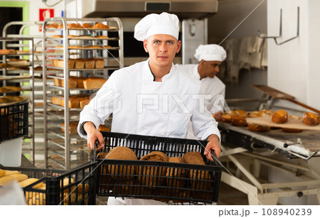 Male baker carrying crate with baked bread 108940239