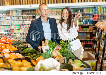 Portrait of a happy young couple in a supermarket with a full grocery cart 108940819