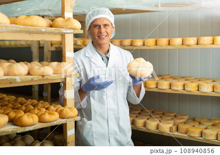 Cheerful cheesemaker standing in ripening room of cheese factory 108940856