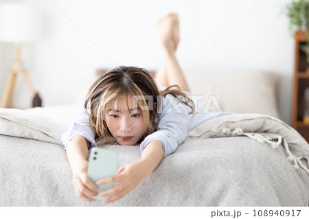 ビューティー ベッドに寝転びスマホを見る女性 ビューティー ベッドに寝転びスマホを見る女性 108940917