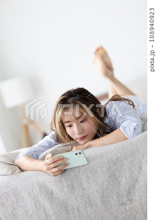 ビューティー　ベッドに寝転びスマホを見る女性 108940923