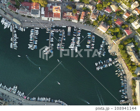 Aerial panoramic view of Balaklava landscape with boats and sea in marina bay on sunset time. Crimea Sevastopol tourist attraction. Drone top view shot of port for luxury yachts, boats and sailboats 108941144