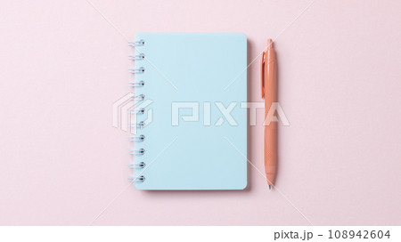 ピンク色の紙の上に置かれたノートとボールペン ピンク色の紙の上に置かれたノートとボールペン 108942604