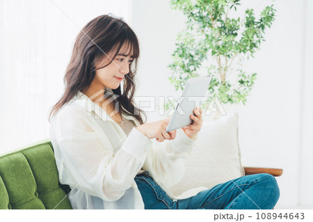 ソファでタブレットを見る女性 108944643