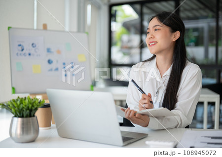 Young beautiful Asian businesswoman working for her client in her office room with laptop and office supplies. Young beautiful Asian businesswoman working for her client in her office room with laptop and office supplies. 108945072
