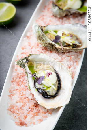 Grilled oysters on red sea salt with lime 108945384
