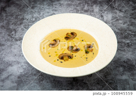 mushroom cream soup with herbs and champignons in a white plate mushroom cream soup with herbs and champignons in a white plate 108945559
