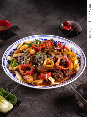 noodles with bell pepper, potatoes, meat and herbs in a plate with a pattern side view 108945708