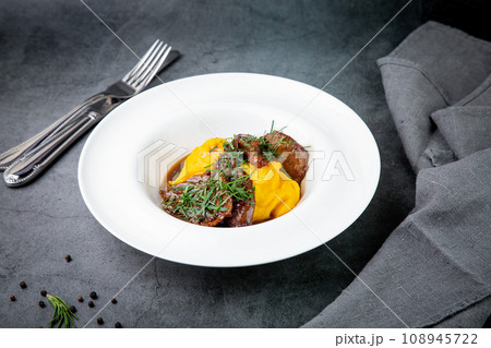 mashed potatoes with meat, sauce and herbs in a deep plate side view 108945722