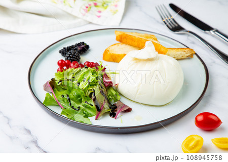 mozzarella with spinach, cherry tomatoes, wild berries and bread in a round plate side veiw mozzarella with spinach, cherry tomatoes, wild berries and bread in a round plate side veiw 108945758