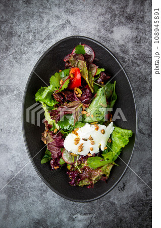 salad with lettuce, radishes, tomatoes, parsley, seeds and cheese top view salad with lettuce, radishes, tomatoes, parsley, seeds and cheese top view 108945891