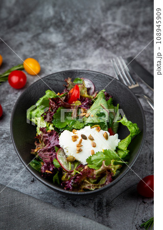 salad with lettuce, radishes, tomatoes, parsley, seeds and cheese side view salad with lettuce, radishes, tomatoes, parsley, seeds and cheese side view 108945909