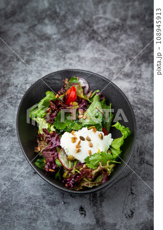 salad with lettuce, radishes, tomatoes, parsley, seeds and cheese side view 108945913
