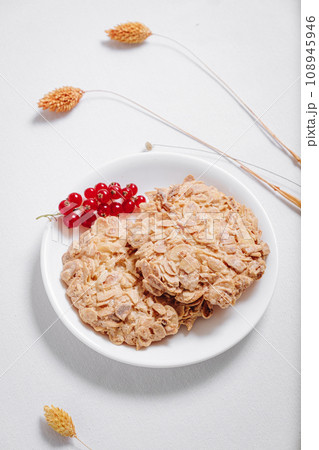 whole grain cookies with a sprig of red currants in a small white plate side view 108945946