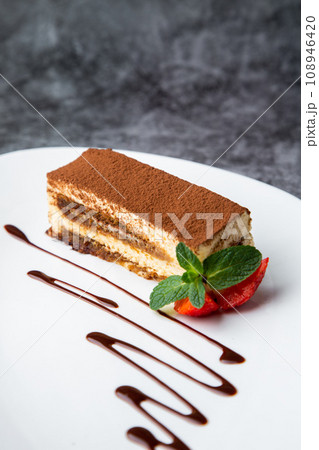 side view of chocolate sponge cake with strawberries and mint on a white plate side view of chocolate sponge cake with strawberries and mint on a white plate 108946420