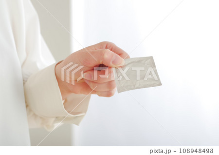 コンドームを手渡す女性の手元 108948498