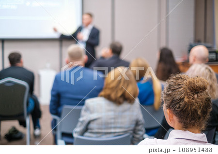 Back view of businesswoman attending presentation with diverse participants in conference hall Back view of businesswoman attending presentation with diverse participants in conference hall 108951488