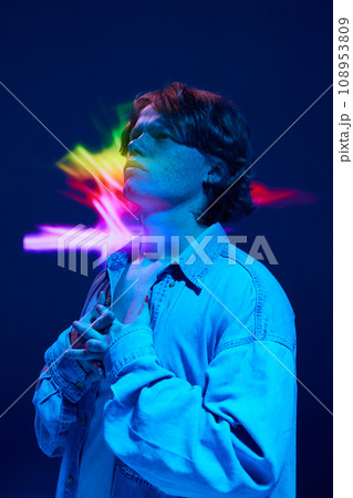 Confused man put hands on breast and looking away in mixed neon light illuminating futuristic, digital projector reflection. Confused man put hands on breast and looking away in mixed neon light illuminating futuristic, digital projector reflection. 108953809