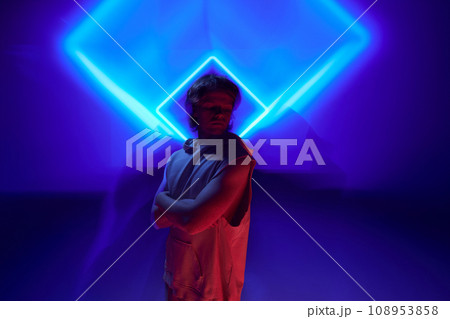 Futuristic portrait of handsome, calm man posing in neon light against background illuminated abstract digital, projector reflection. Futuristic portrait of handsome, calm man posing in neon light against background illuminated abstract digital, projector reflection. 108953858
