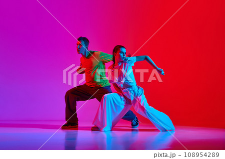Young talented people, man and woman dancing street style dance, hip hop against pink red background in neon light Young talented people, man and woman dancing street style dance, hip hop against pink red background in neon light 108954289