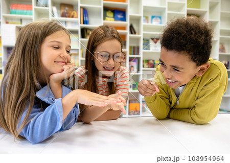 Children sitting in school library having fun while break Children sitting in school library having fun while break 108954964