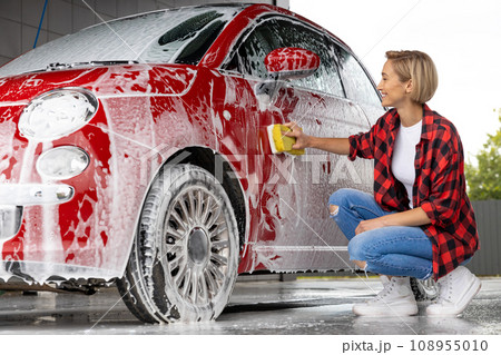 Blonde woman cleaning the car door with a foam Blonde woman cleaning the car door with a foam 108955010