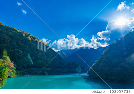 富山県黒部市　うなづき湖と色づき始めた山並み 108957738