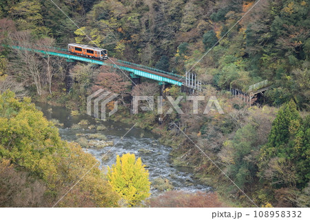 水郡線「久慈川と山間部の鉄橋を走るオレンジ色の列車」 108958332