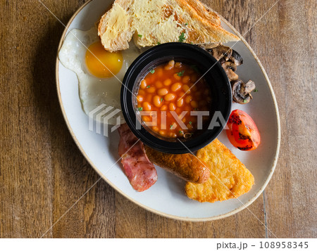 Full English breakfast with beans and sausage served on wooden table Full English breakfast with beans and sausage served on wooden table 108958345