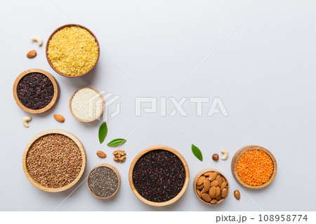 Various superfoods in smal bowl on colored background. Superfood as rice, chia, quinoa, lentils, nuts, sesame seeds, almonds. top view copy space 108958774