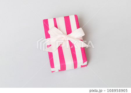wrapped Christmas or other holiday handmade gift box in color paper with ribbon on colored background. Present box, decoration of gift on colored table, top view with copy space 108958905